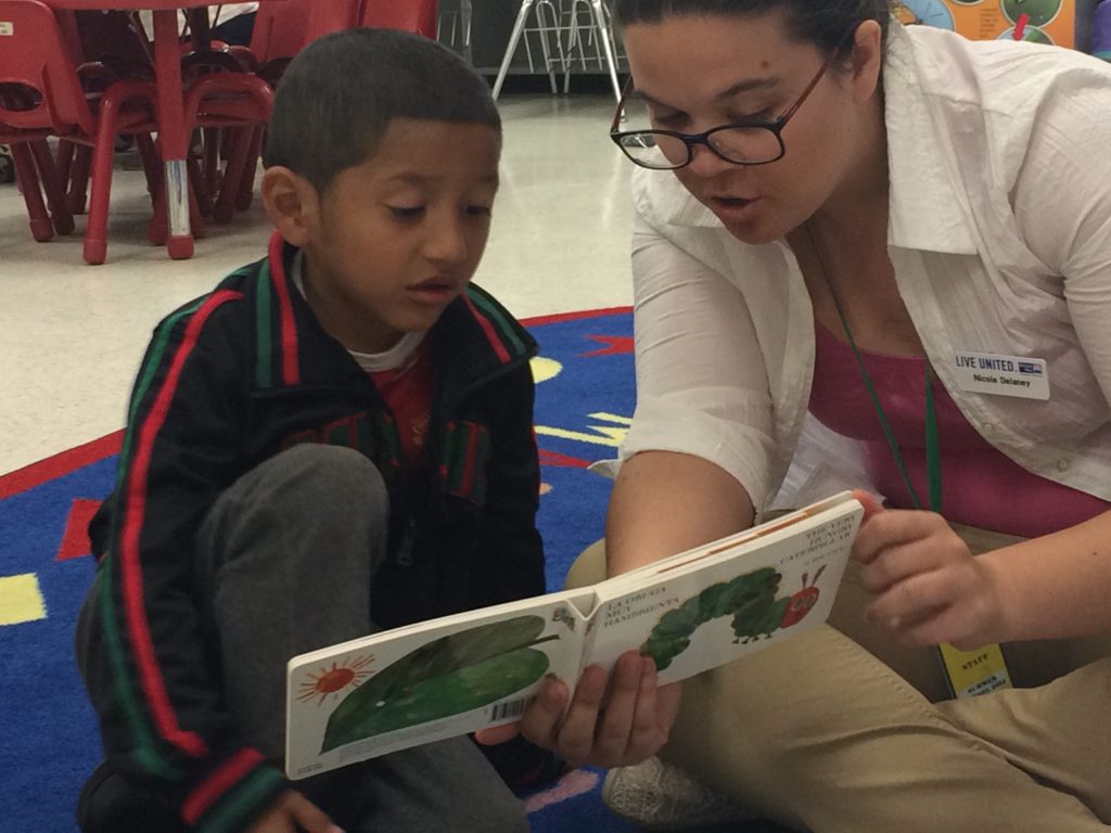 VISTA Nicole Delaney helps a child read at Kindergarten Camp